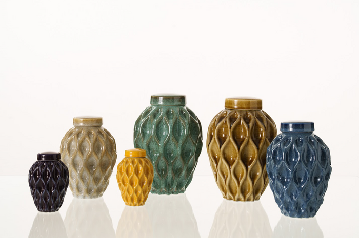 Set of six glazed ceramic urns in varying colors with flowing lattice patterns arranged on a light background