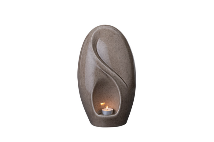 Eternity Ceramic Urn in warm beige with an integrated candle holder and graceful flowing curves.