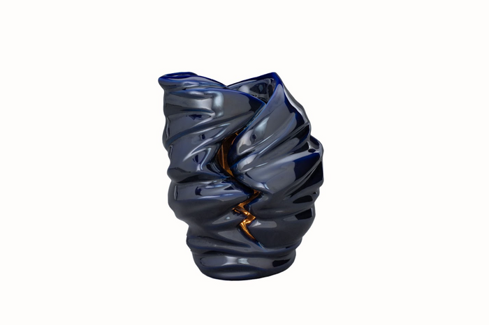 Deep blue glossy sculptural candle urn with a tealight glowing inside.