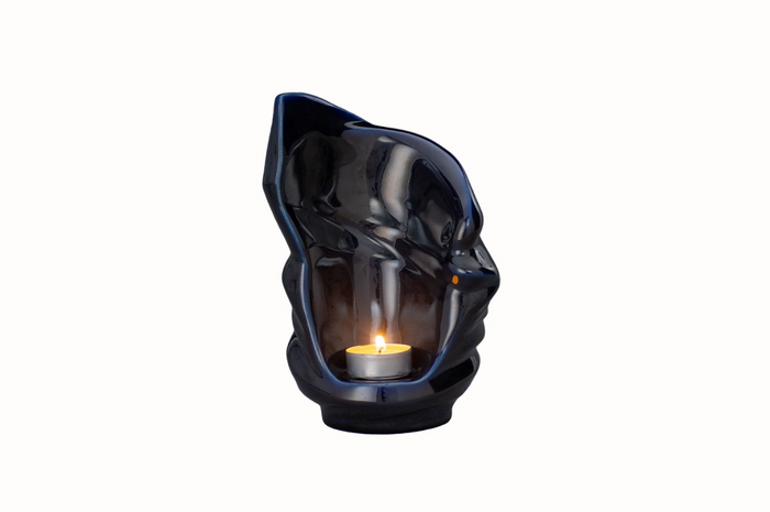 Blue twisted ceramic candle urn with inner glow from a lit tealight.