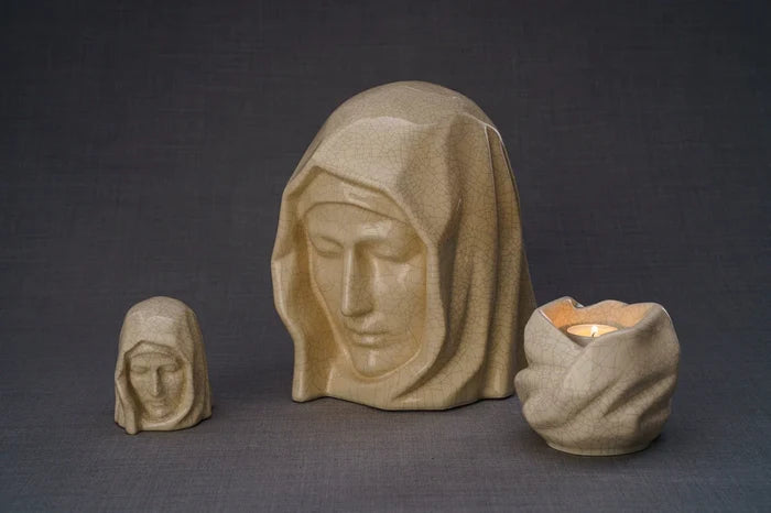 Beige Holy Mother sculpture with a candle holder and a smaller bust beside it on a textured gray surface